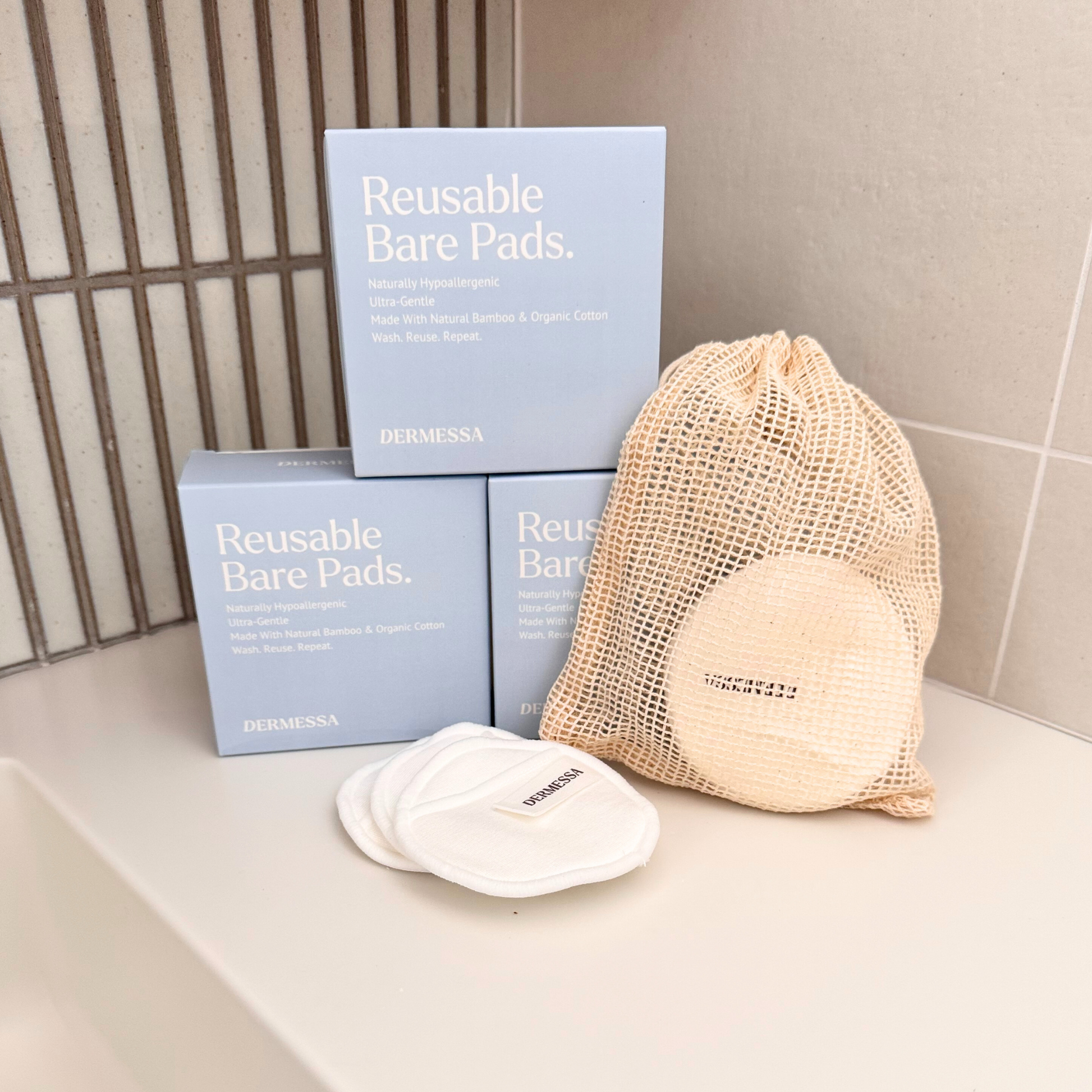 Reusable bare pads with packaging and a mesh bag on a bathroom counter.