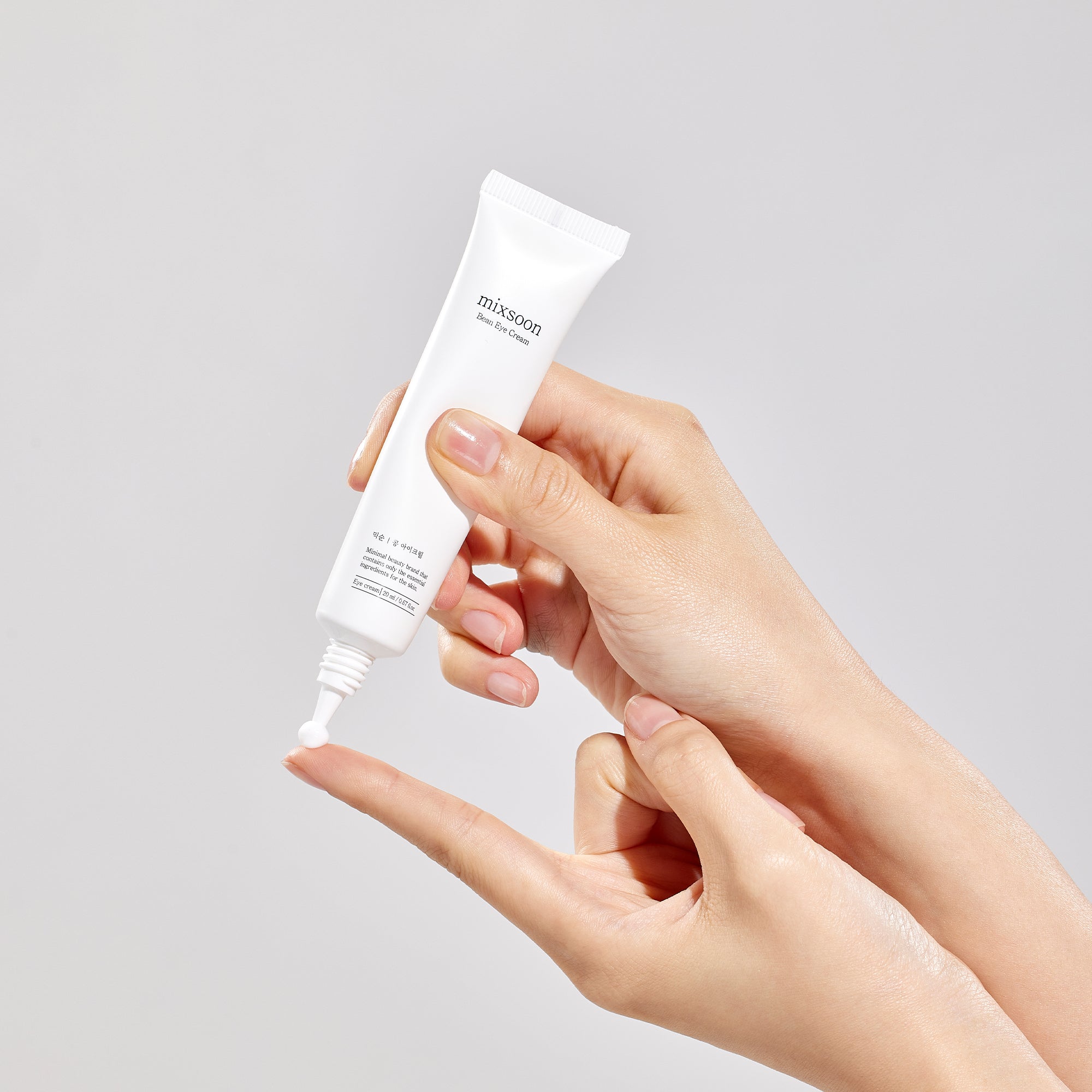 Mixsoon Bean Eye Cream tube being dispensed onto a fingertip against a neutral background.