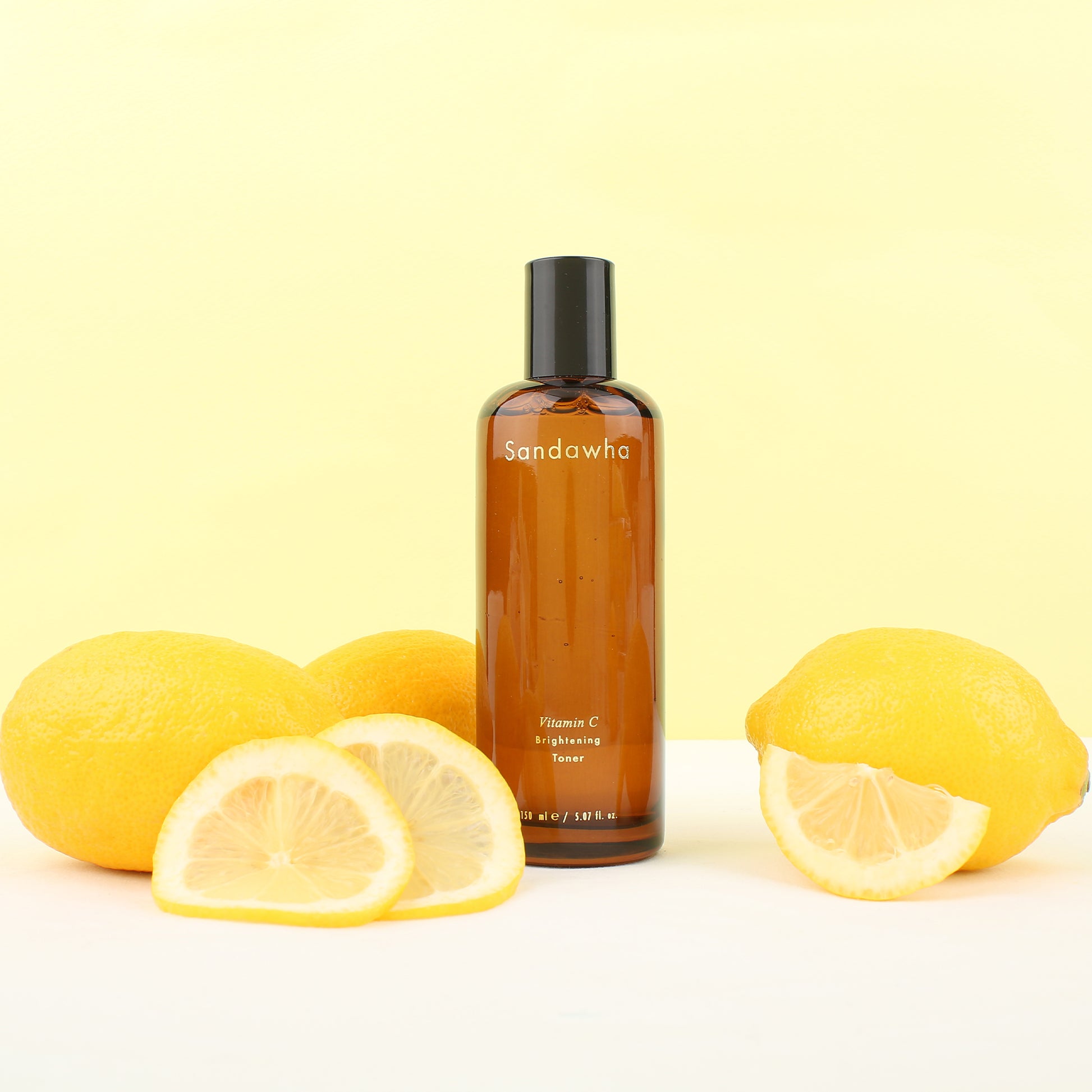 Sandawha Vitamin C Brightening Toner with lemons on a yellow background.