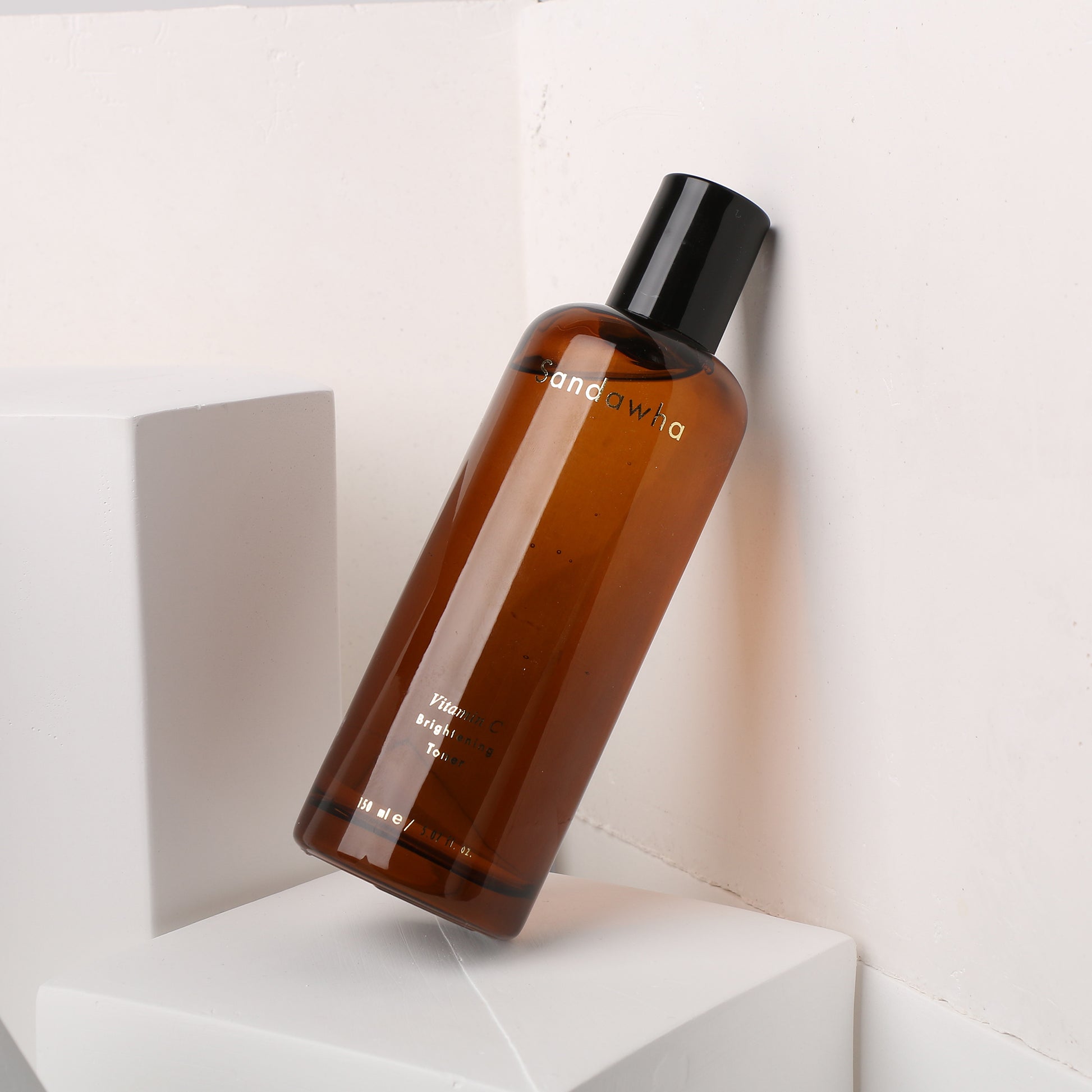 Sandawha Vitamin C Brightening Toner in amber bottle on geometric white background.