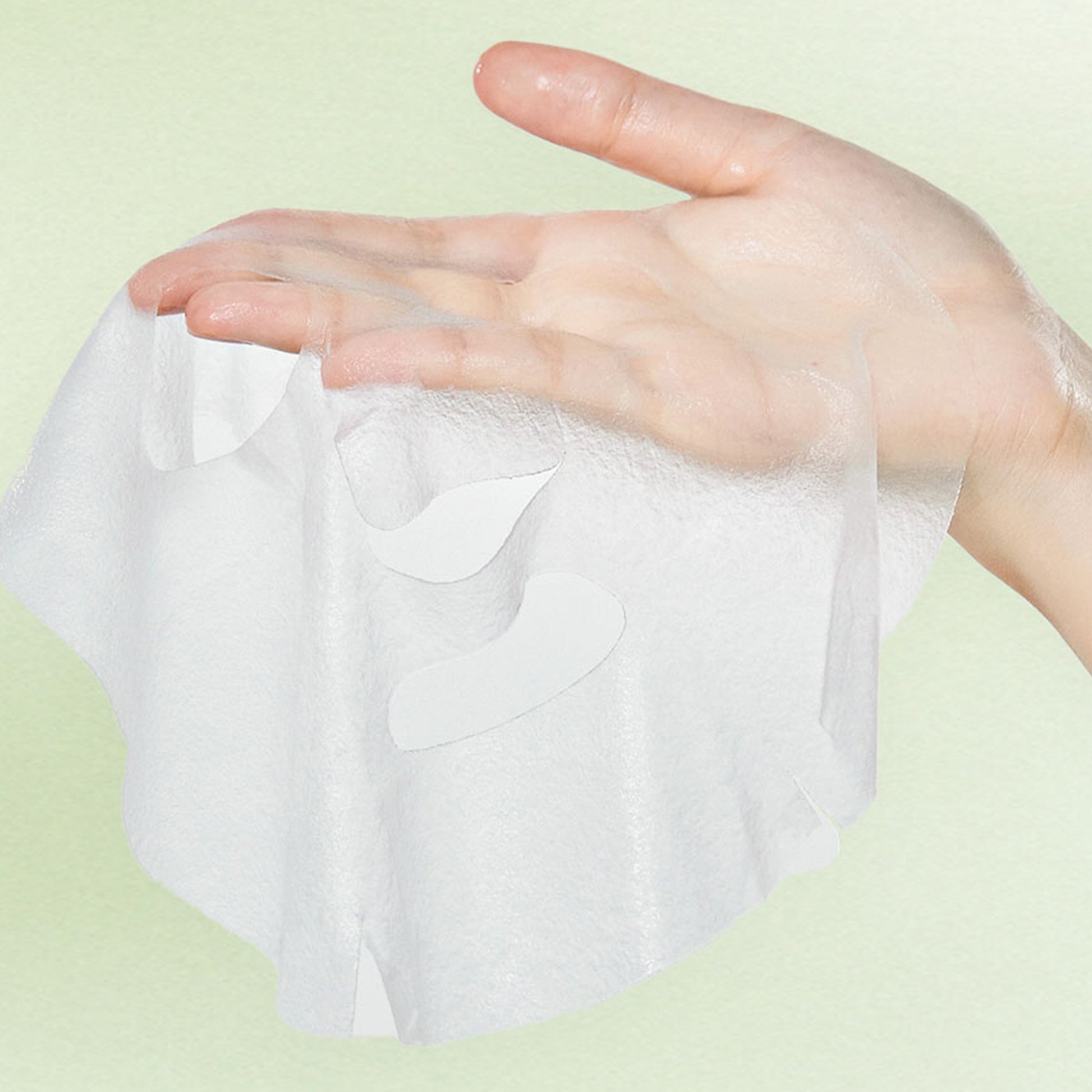 Hand holding Centella Asiatica face mask sheet, highlighting texture and material.