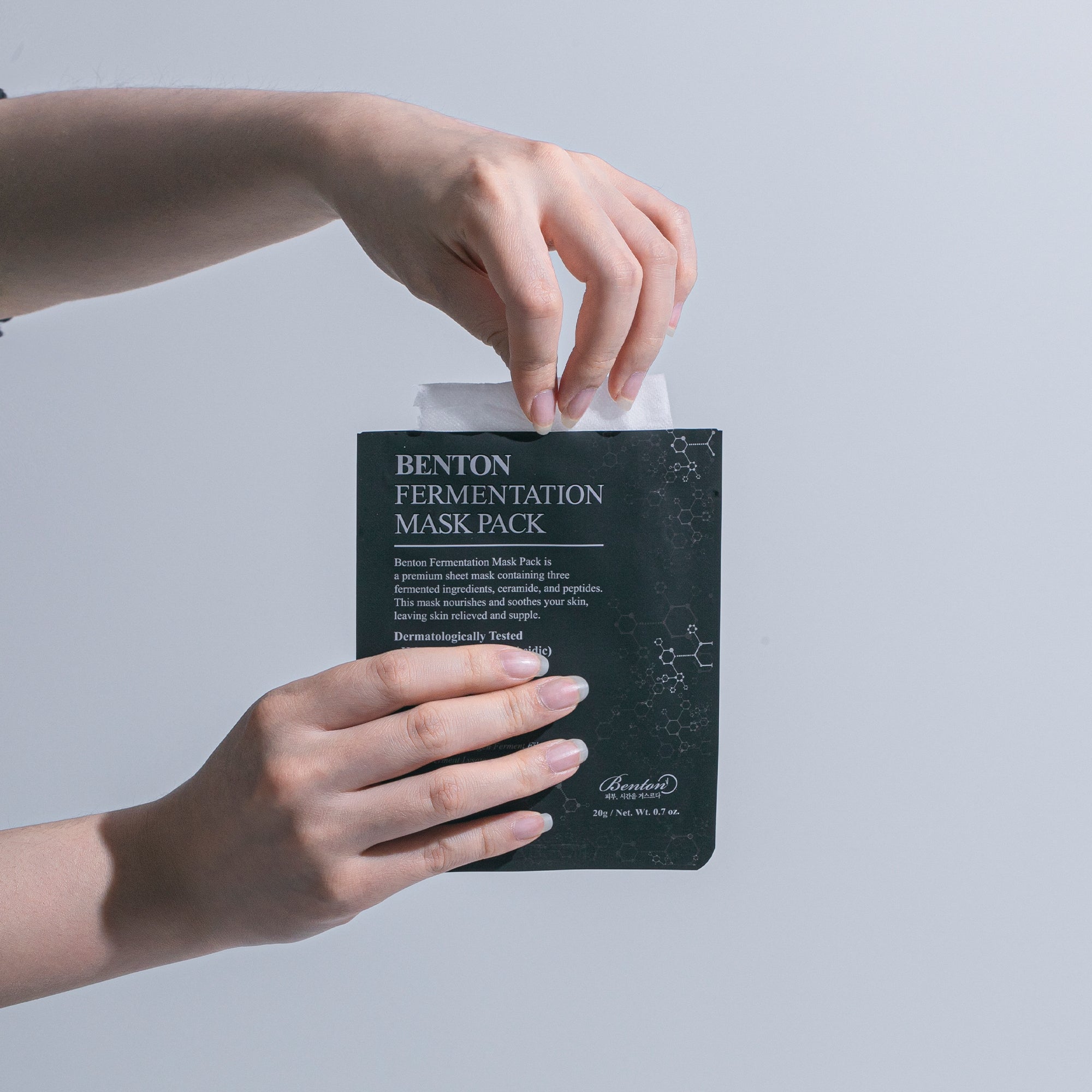Benton Fermentation Mask Pack held by hands, showcasing the packaging and product sheet.