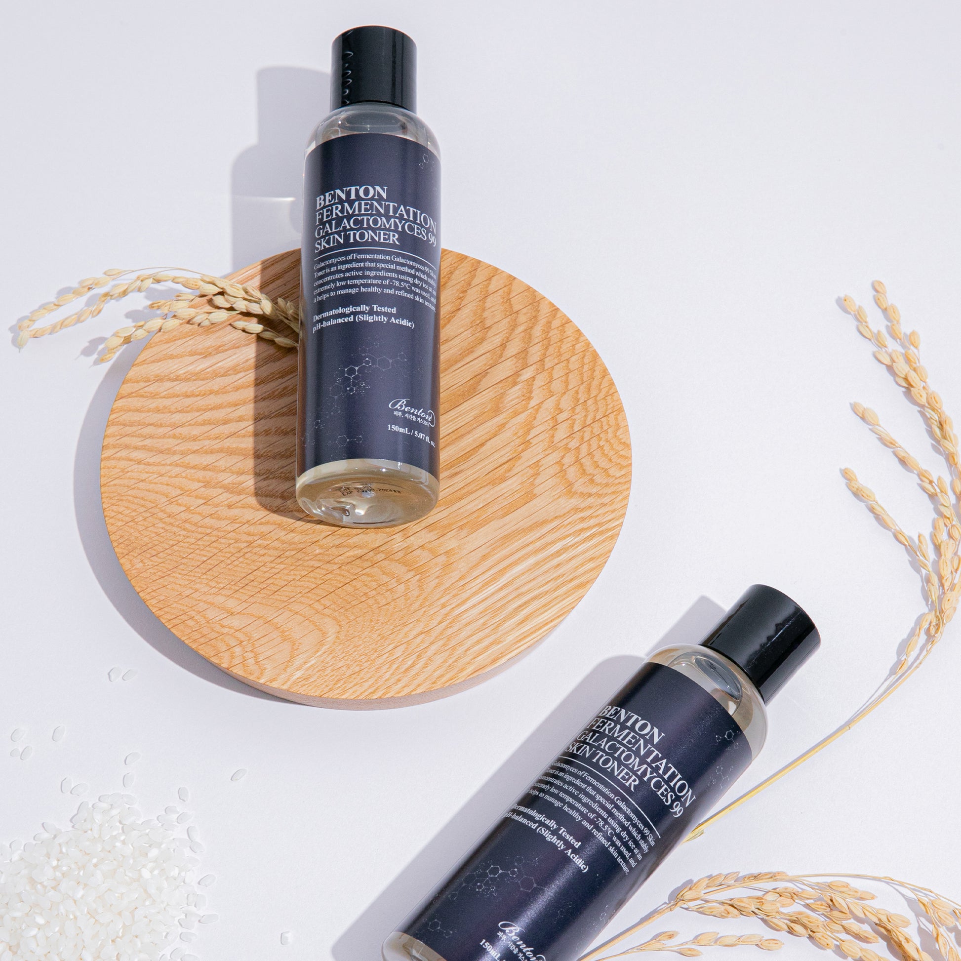 Benton Fermentation Galactomyces 99 Skin Toner bottles on wooden plate with rice grains