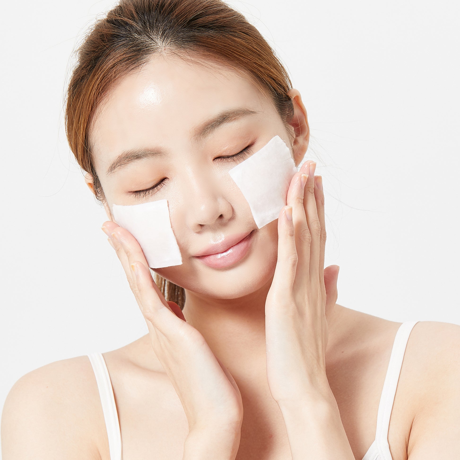 Woman using Galactomyces Toner with cotton pads on her cheeks for skincare treatment.