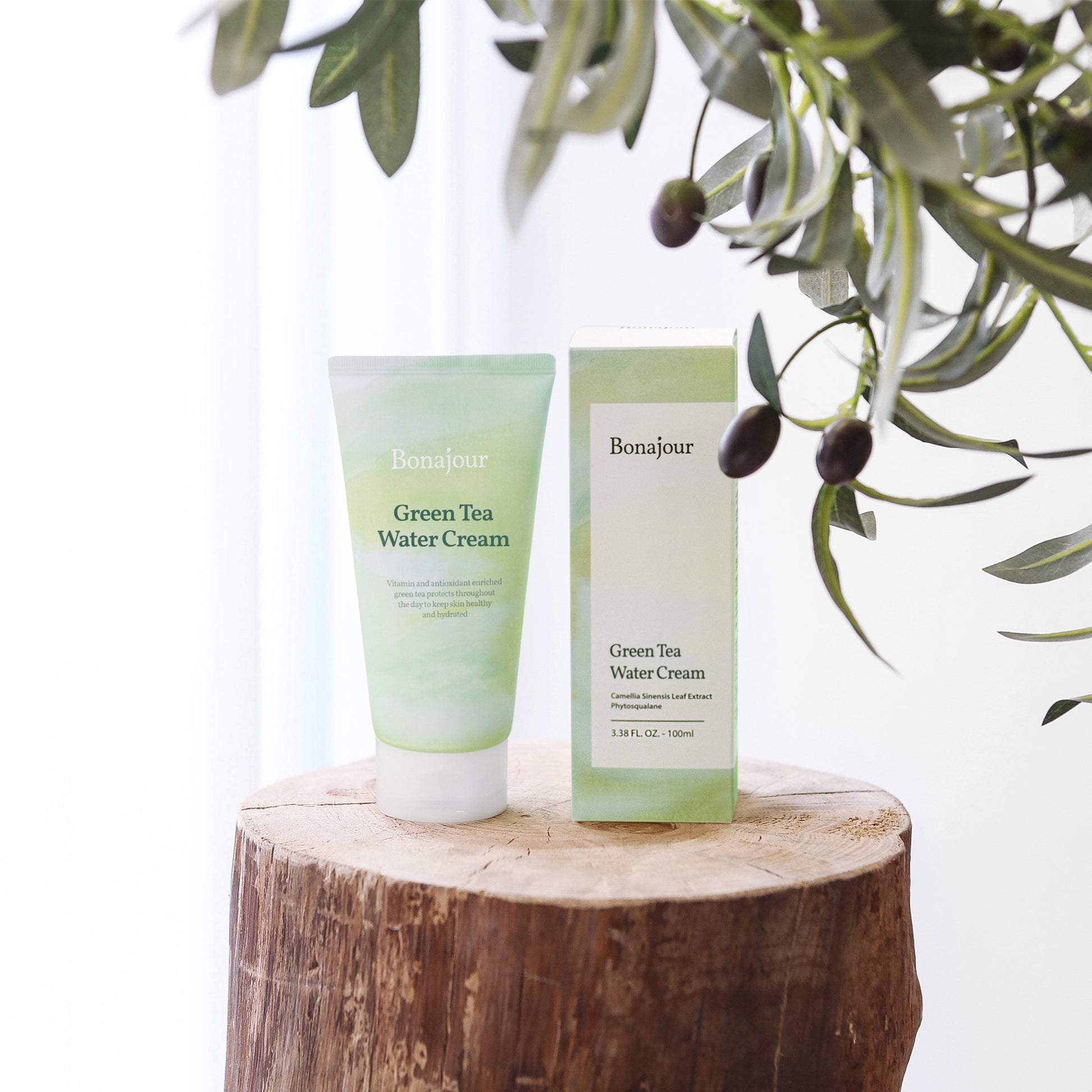 Bonajour Green Tea Water Cream tube and box displayed on a wooden surface with green leaves in the foreground.