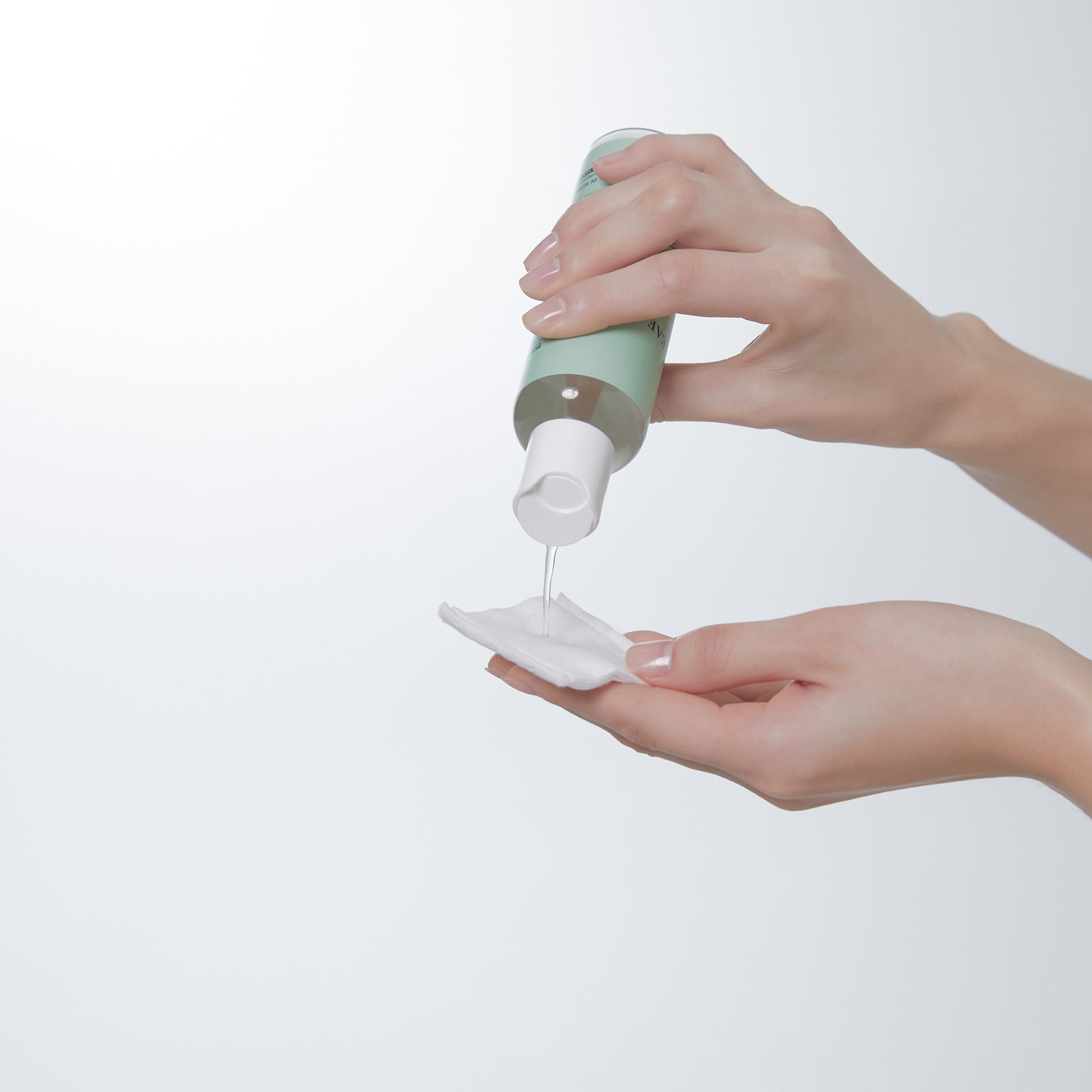 Heartleaf Toner by Abib being applied to a cotton pad from a bottle in hands.