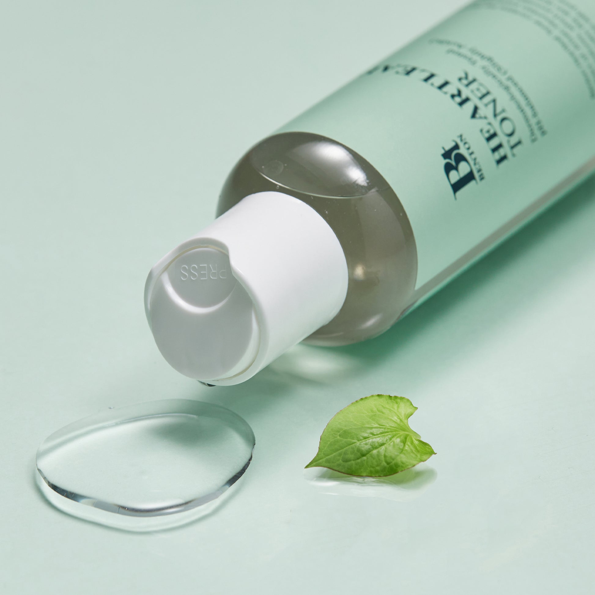 Heartleaf Toner by Brand on mint background with leaf and liquid droplet.