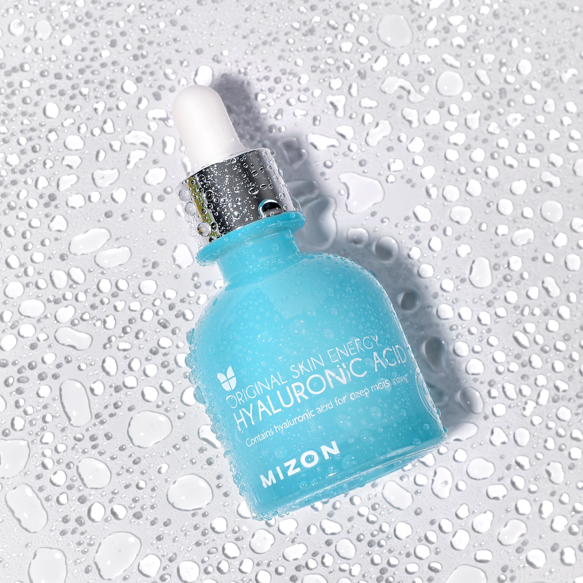 Mizon Hyaluronic Acid serum bottle with dropper, water droplets on surface for hydration effect.