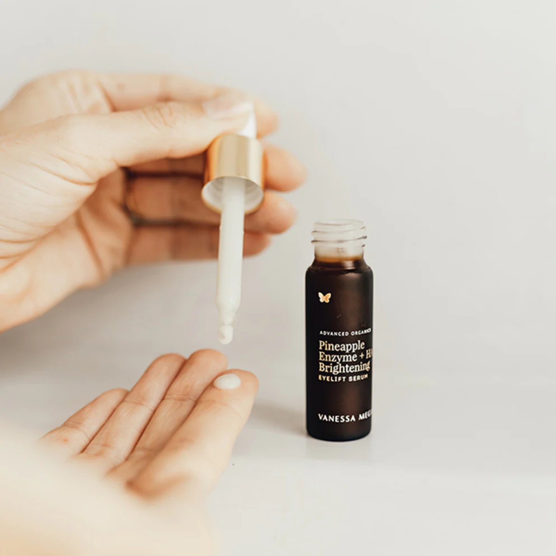 Vanessa Megan Pineapple Enzyme + HA Brightening Eyelift Serum being applied with a dropper on a light background