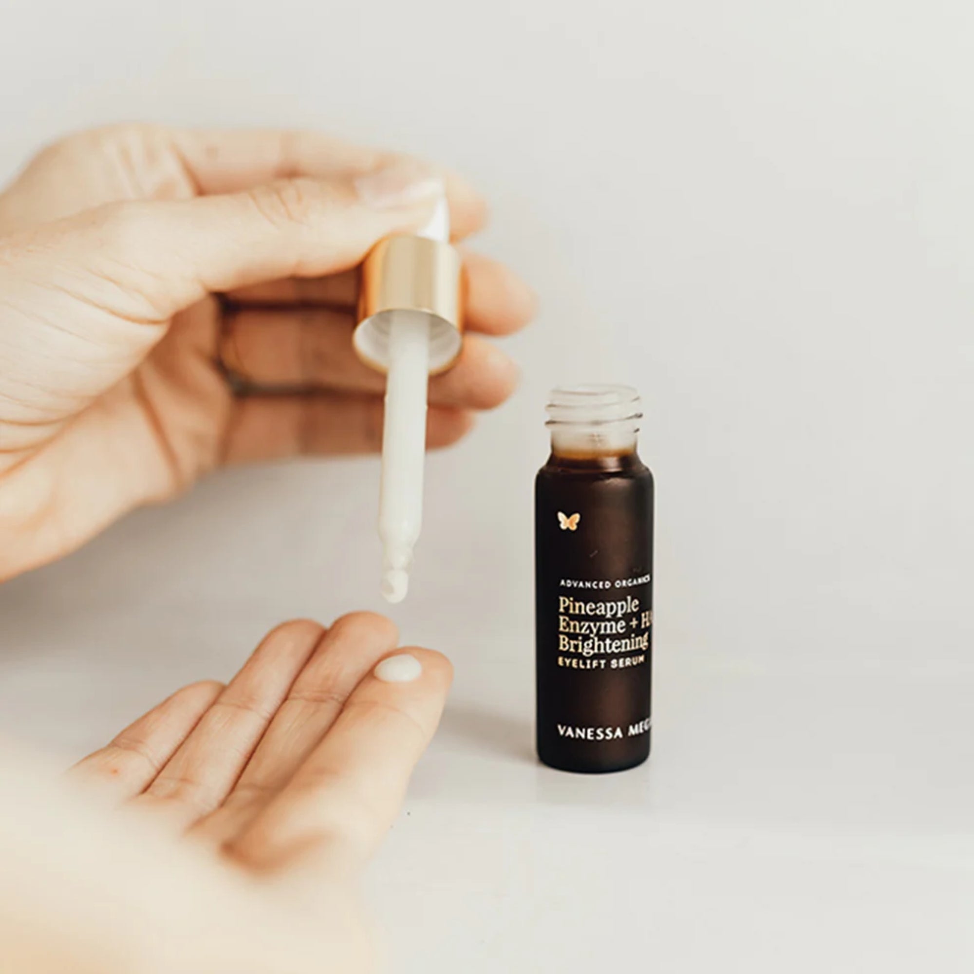 Vanessa Megan Pineapple Enzyme + HA Brightening Eyelift Serum being applied with a dropper on a light background