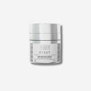 Image of a jar labeled Naked Chemist Reset Age Defying Cream, containing NZ Manuka and Retinol, with a silver lid and decorative patterns on a white background.