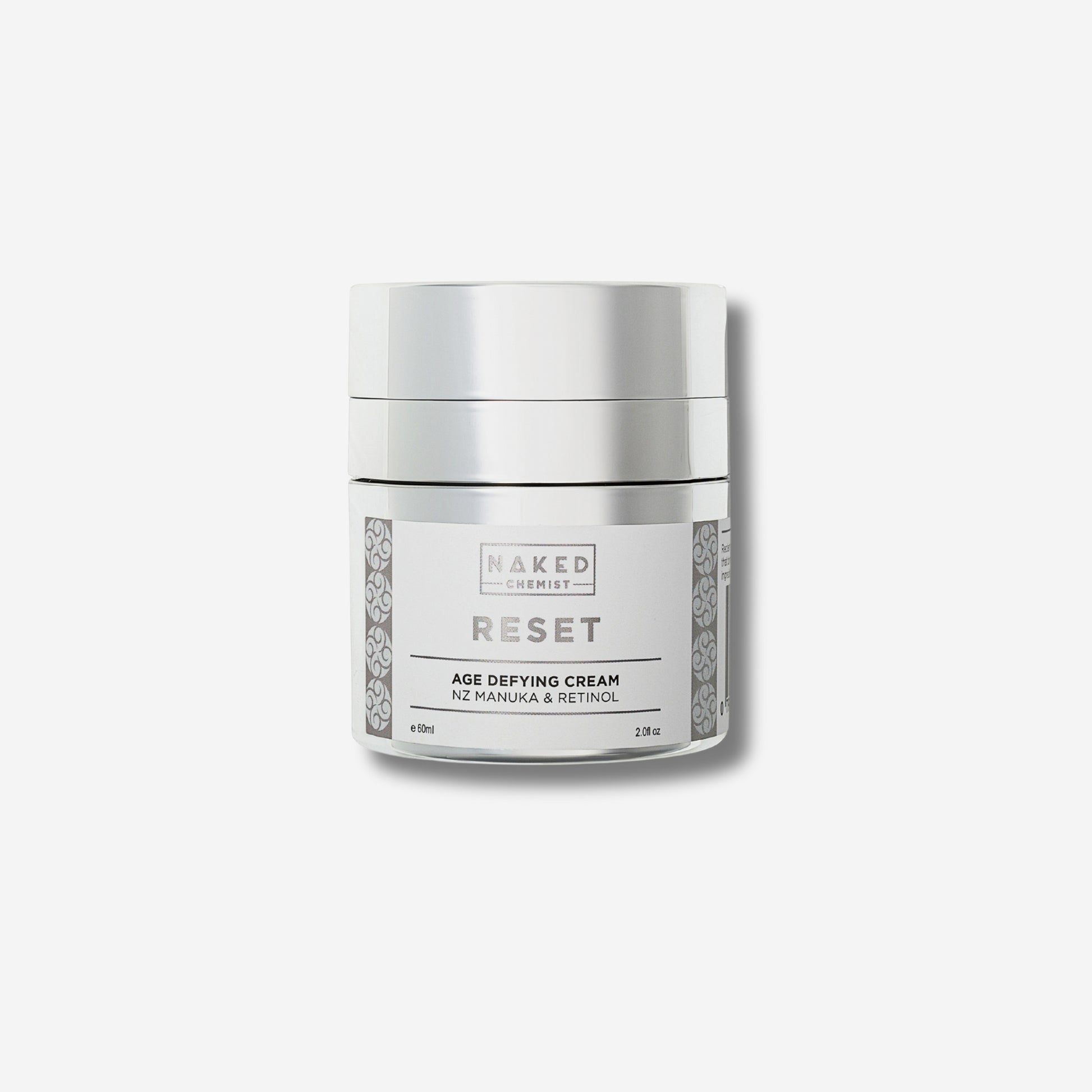 Image of a jar labeled Naked Chemist Reset Age Defying Cream, containing NZ Manuka and Retinol, with a silver lid and decorative patterns on a white background.