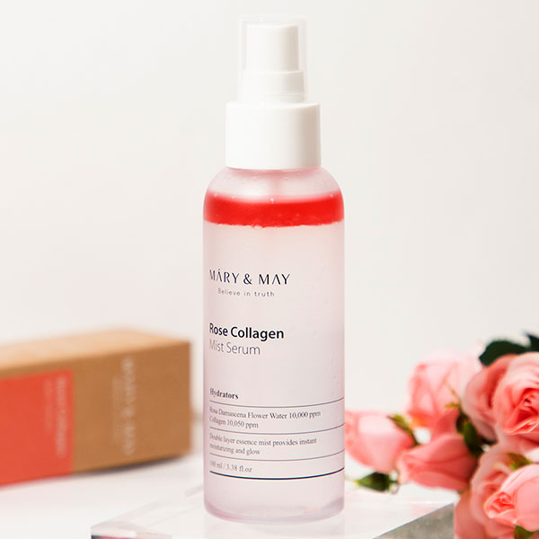 Mary & May Rose Collagen Mist Serum bottle displayed with pink roses and a product box in the background.