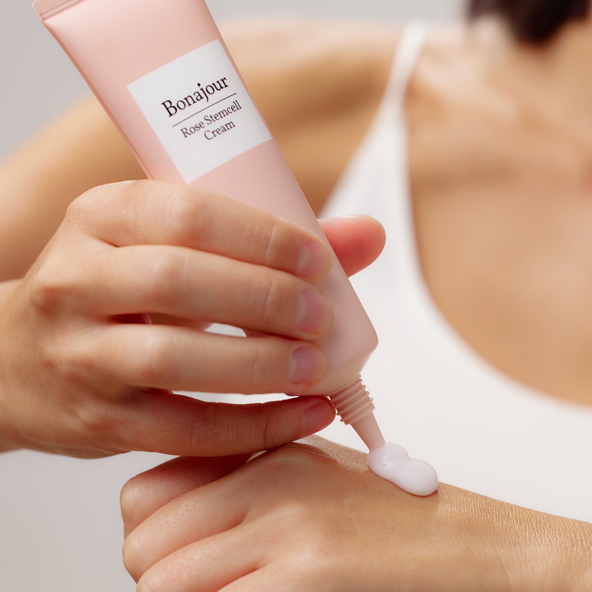 Person applying Bonajour Rose Stemcell Cream from a pink tube onto their hand.