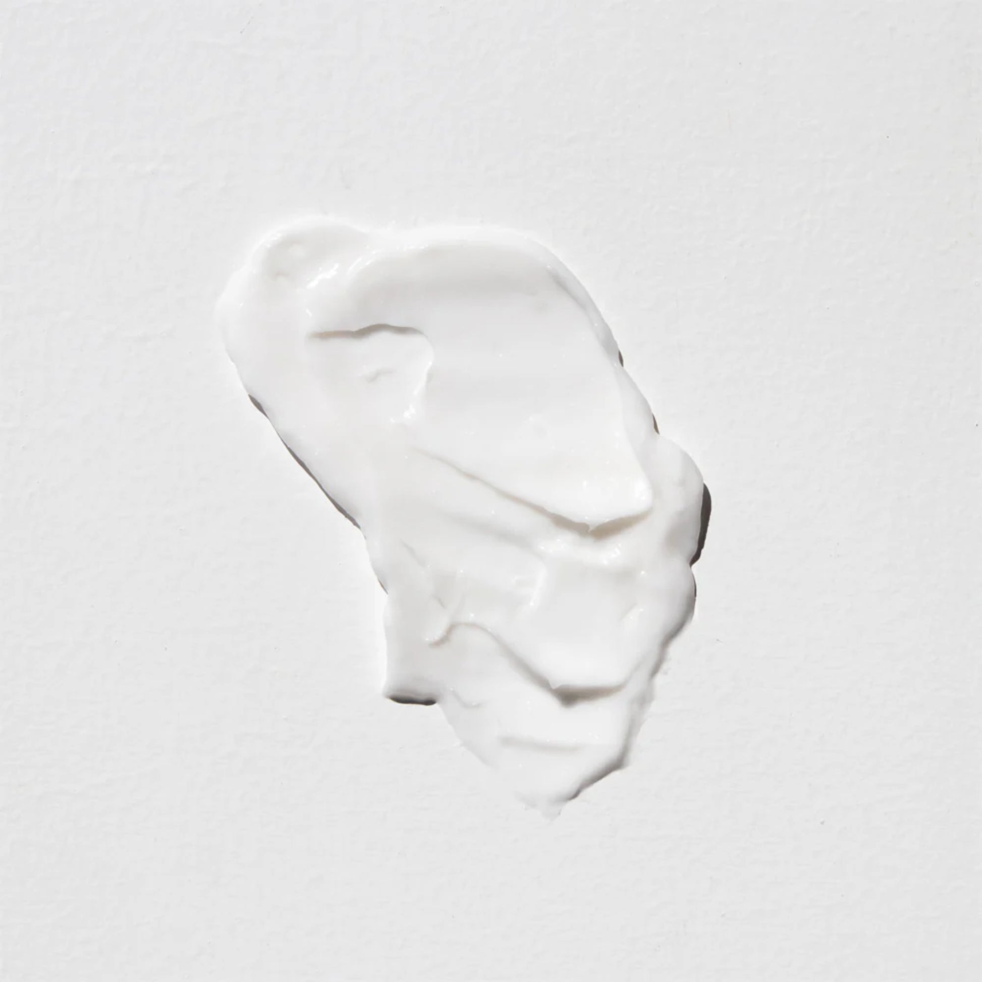 White cream or paint swatch on a light grey background