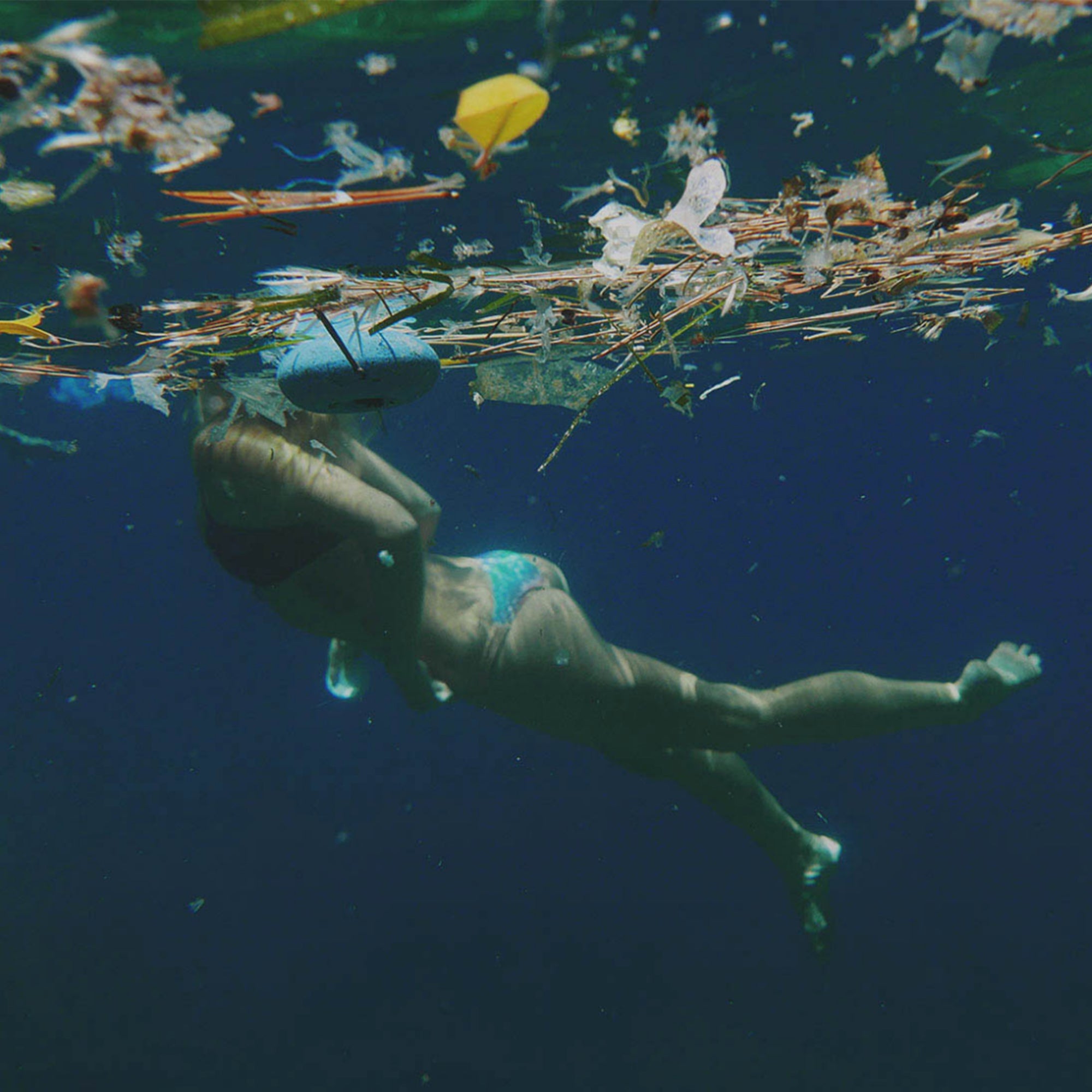 A lady swimming in an ocean full of rubbish