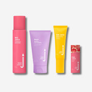 Four Skin Juice products on a white background. From left to right: a pink bottle labeled 'Bio Juice Hydrating Skin Drink,' a purple tube labeled 'Pulp Refining Clay Cleanser,' a yellow tube labeled 'Sun Juice Mineral SPF 15,' and a pink tinted balm stick with watermelon imagery labeled 'Pink Juice.'