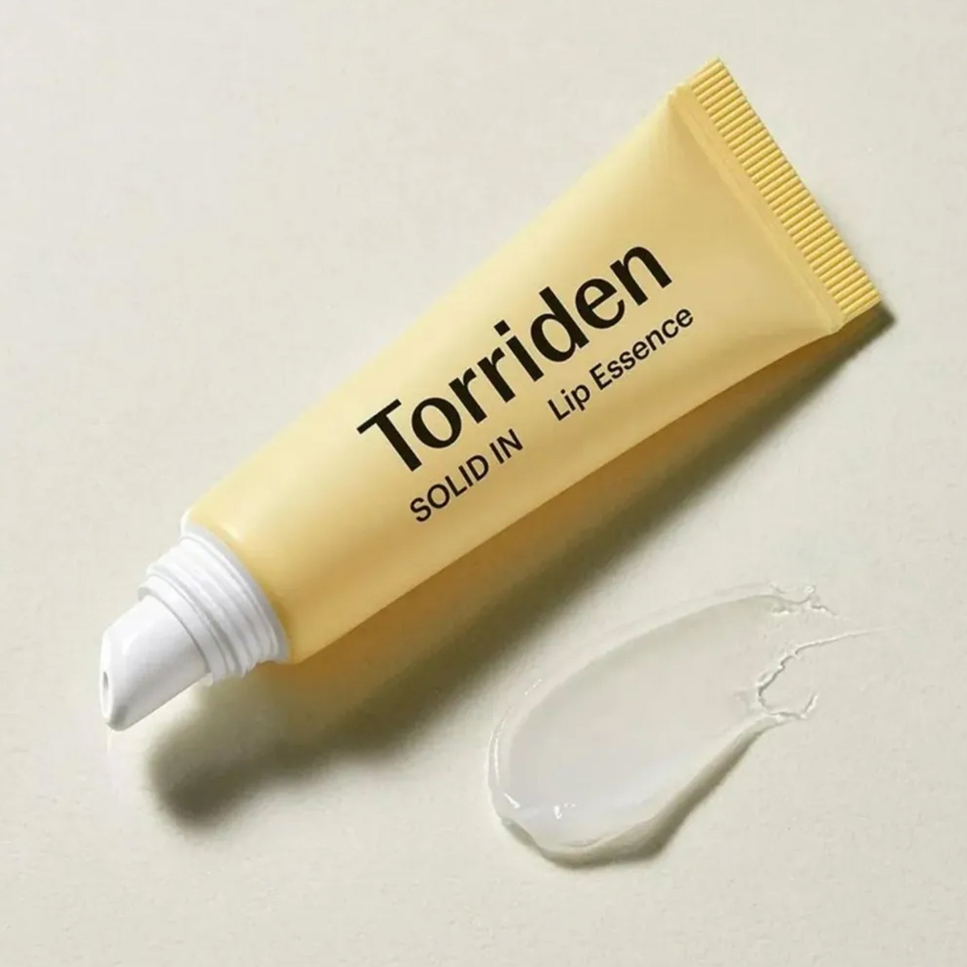 Torriden SOLID IN Ceramide Lip Essence tube with clear gel swatch on surface.