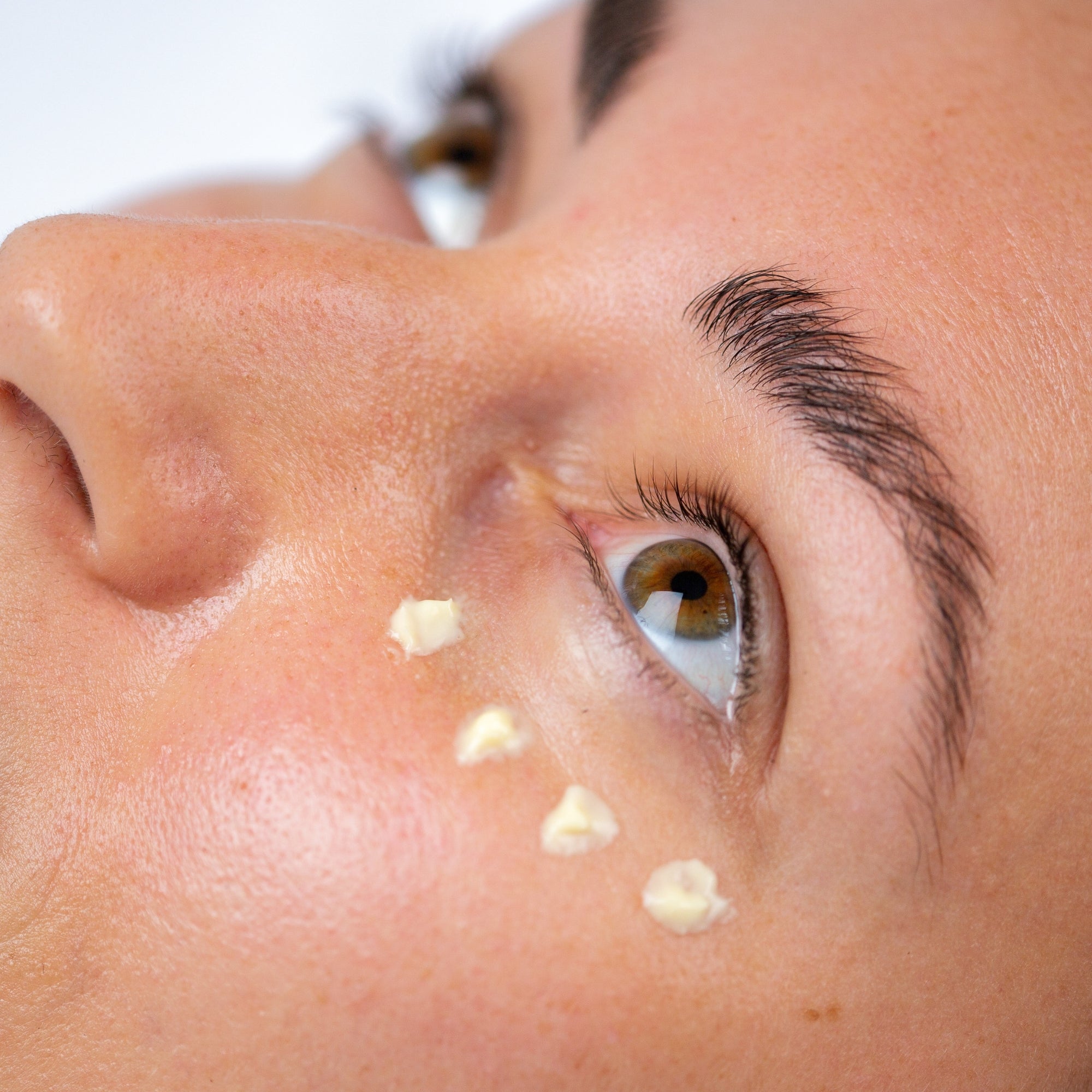 Close-up of a person's eye with eye cream on their face