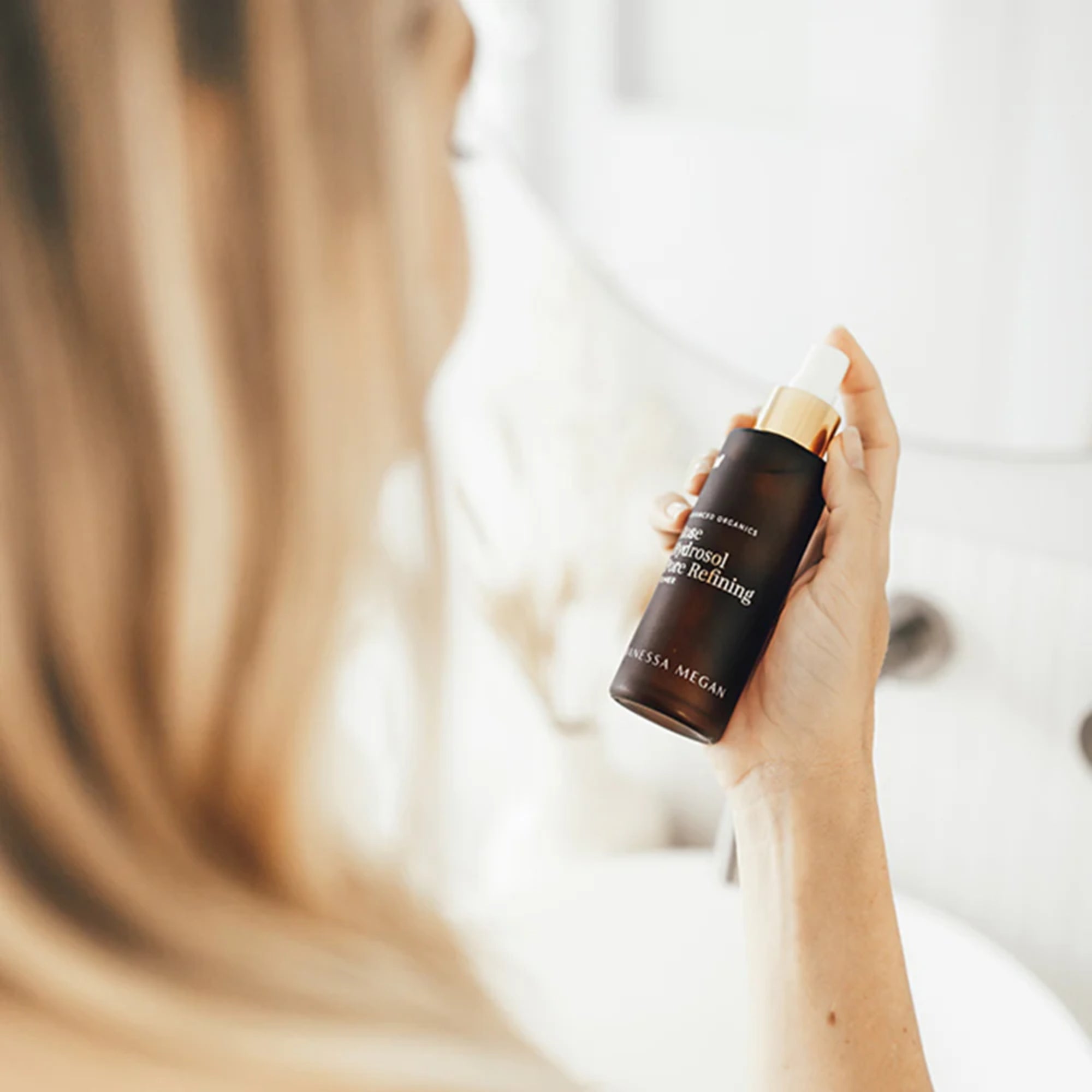 Hand holding a bottle of Vanessa Megan Rose Hydrosol Pore Refining Toner  with a blurred background