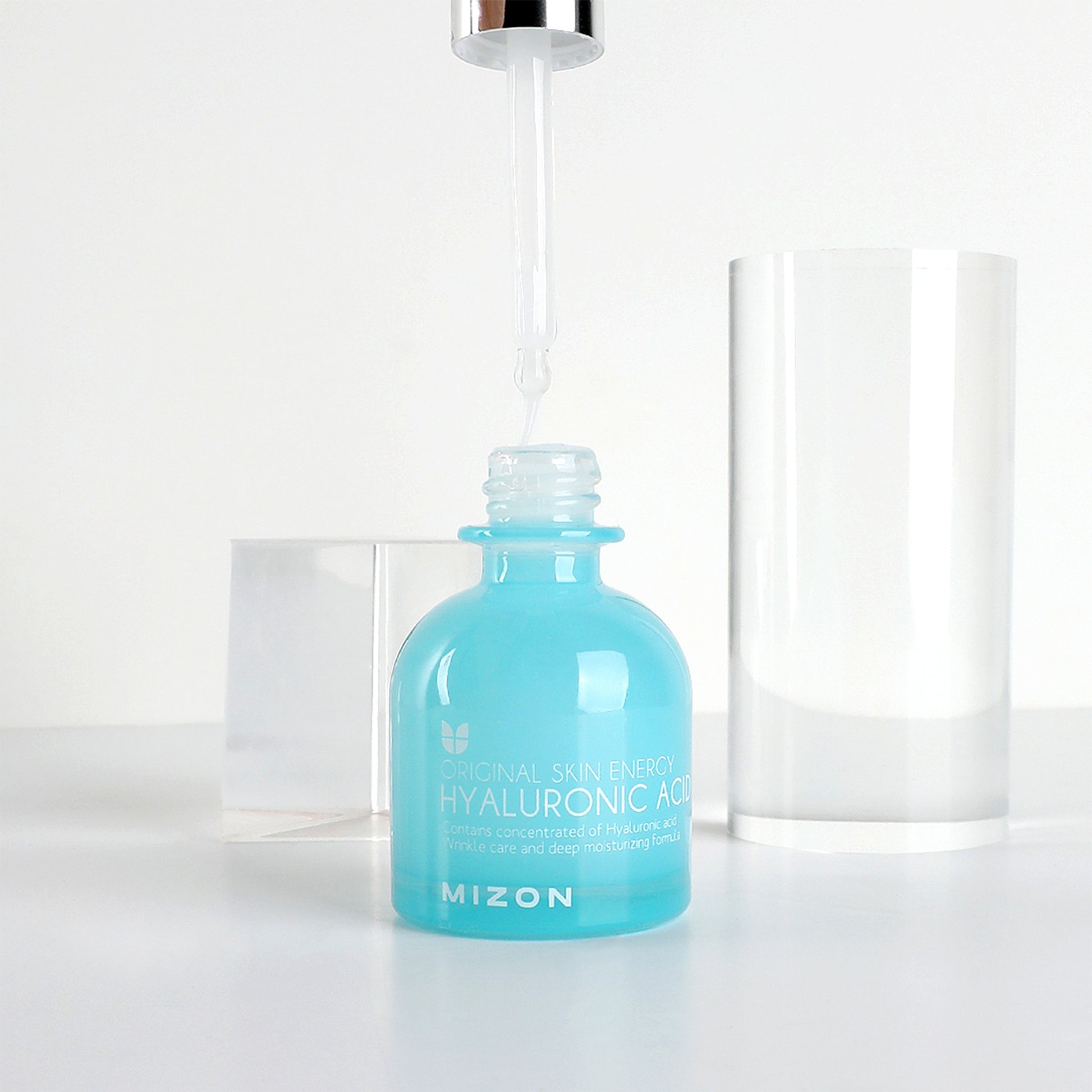 Mizon Hyaluronic Acid serum bottle with dropper, clear cylinder cap beside it.