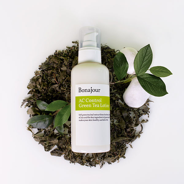A bottle of AC Control Green Tea Lotion by Bonajour, an ideal face lotion for oily skin, surrounded by green tea leaves and white decorative balls.