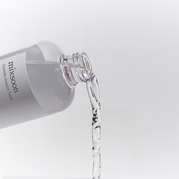 A bottle labeled "Centella Asiatica Toner" pouring liquid out on a plain background, showcasing the best toner for face care.